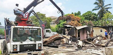 A demolition crew on Sunday clears the wreckage of the burned-out building.
