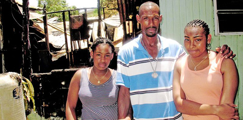 Johnny Buttrum and his daughters Hanielle, 12, and Janielle, 14, survey the wreckage of their George Town home on Saturday.