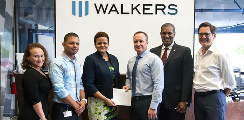 Education Minister Tara Rivers and Winston Connolly, councilor to the minister, accept a check for music programs in the schools from Walkers partners Tim Buckley and Rolf Lindsay.