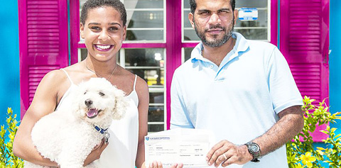 Melanie Moore, with her dog Bones, presents a check to Jason Jairam of the Humane Society on Thursday.