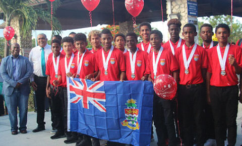 Cayman Islands Football Association acting president Bruce Blake, left, and Sports Minister Osbourne Bodden, second from left, welcome home the U-15s at the airport on Tuesday.
