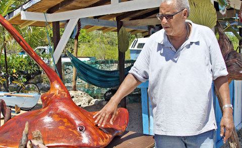 Edney McLean shows off a stingray he carved from a single piece of driftwood found in East End. – Photos: Charles Duncan