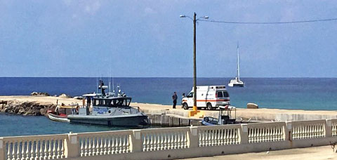 An RCIPS marine vessel docks in Cayman Brac Tuesday alongside a boat police found adrift with two decomposing bodies on board and towed to shore.