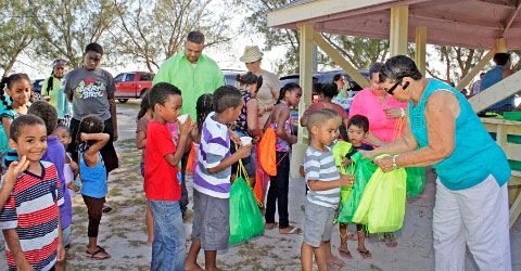 Students line up to receive bags of school supplies put together and distributed by committee members, from right, Alex Johnson, Felisiana Ebanks, Marilyn Hines and Jay Ebanks. - PHOTOS: CAROL WINKER