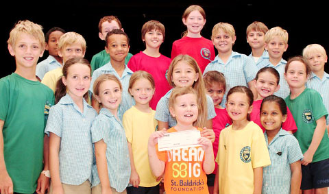 Hannah Meeson receives a check for $12,000 for childhood cancer research from Cayman Prep’s student council after the school staged a fundraising coin-drop. – Photo: Jewel Levy
