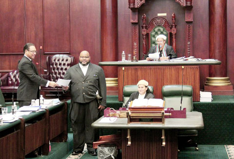 Premier Alden McLaughlin, left, hands the legislative order authorizing the acceptance of a boundary commission report recommending 19 single-member voting districts to the Legislative Assembly