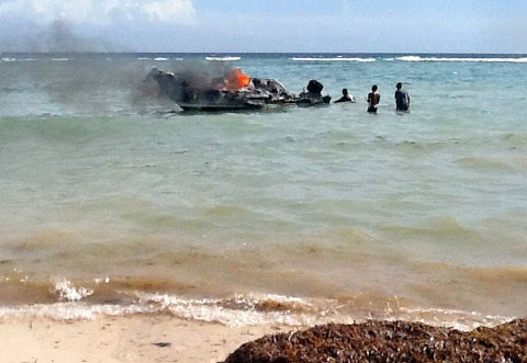 Residents pull the still burning boat to shore in North Side Thursday morning. – PHOTO: CAROL WINKER