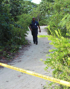 A Royal Cayman Islands Police officer walks through the area just off Grand Cayman’s Seven Mile Beach where a woman’s body was found early Sunday. – Photo: Brent Fuller