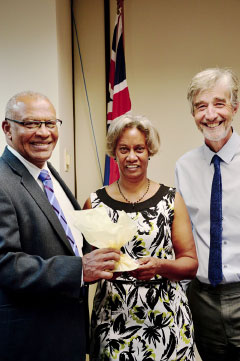 Retiring Court Officer Ermyn Berry is flanked by Chief Justice Anthony Smellie, presenting a gift, and Court Administrator Kevin McCormac.
