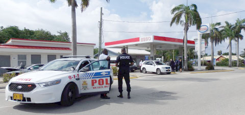 Police stand guard as members of the court visit the Hell gas station in West Bay, where 4-year-old Jeremiah Barnes was shot and killed in 2010. - PHOTO: CAROL WINKER