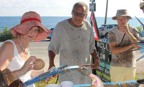 Sylvia Glover and her husband purchase crafts from Mr. McLean’s art stall next to the East End blow holes.