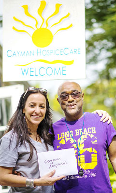 Compass sports editor Ron Shillingford hands over a donation from the sale of sports photos to Danielle Coleman of Cayman HospiceCare on Thursday. - PHOTO: TANEOS RAMSAY