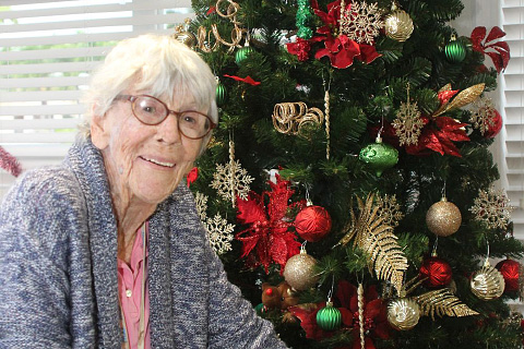 Resident Brenda Quin poses by the Christmas tree.
