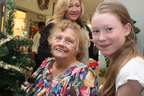 Crystal Corkish, right, and Pamela Webster help resident Naomi Oyog decorate a Christmas Tree.