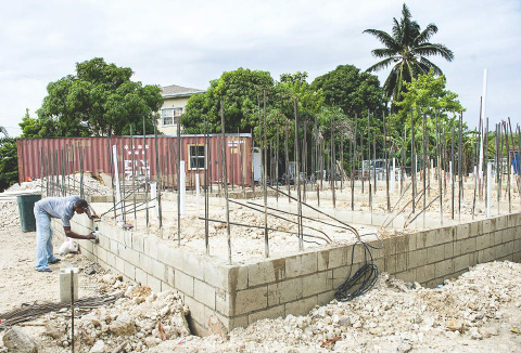 Alwin Buttrum works on rebuilding his home, which burned down in July. – Photo: Taneos Ramsay