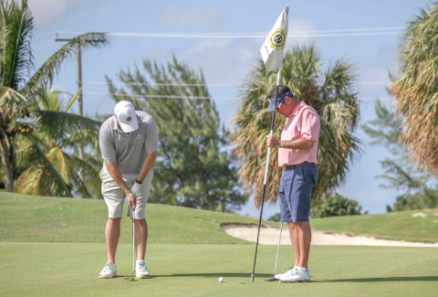 Chris Kirkconnell putts as former PGA Championship winner Rich Beem holds the flag.