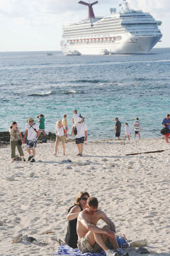 A cruise ship moors off Spotts Dock on Shamrock Road as tourists relax on the nearby beach.