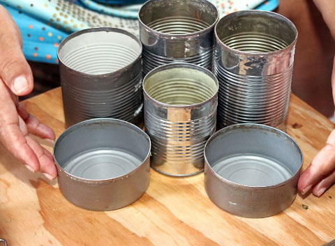 Mrs. Dixon arranges tin cans that will be sprayed black and used as desk caddies.