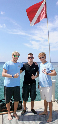 Lobster Pot staff Ryan Campsie and Steven Wright congratulate Andrew Schirn, center, after he passed his divemaster qualification.