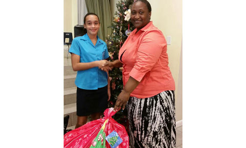 Nadia Simmonds, left, hands over gifts donated by her friends to Dorline Welcome of the Cayman Islands Department of Children and Family Services.