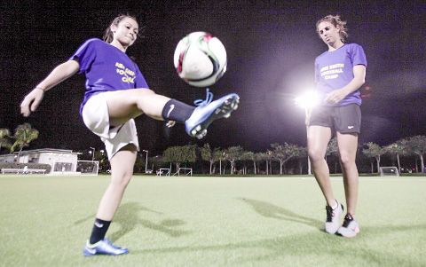 U.S. national team player Carli Lloyd kicks the ball around with Cayman Islands national team player Arie Smith. - PHOTO: MATT LAMERS