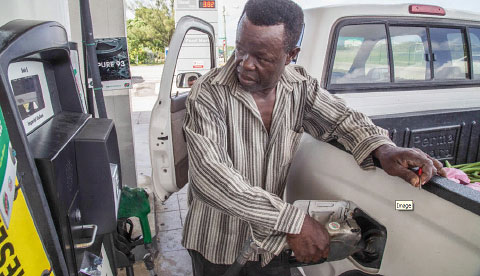 George Town resident Wesley Douglas fills his tank at the Rubis gas station on Crewe Road. Mr. Douglas said he’s happy about falling prices, but said they have room to drop further.