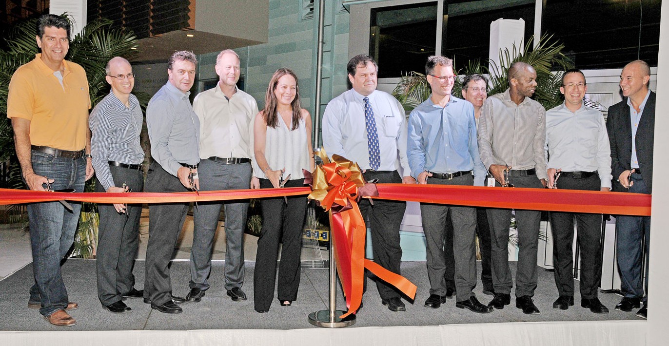 Representatives of PwC, DECCO and Dart Realty, including Chief Operating Officer Jackie Doak, fifth from left, as well as Financial Services Minister Wayne Panton, sixth from left, get ready to cut the ceremonial ribbon and officially open 18 Forum Lane on Wednesday. – Photo: Alan Markoff