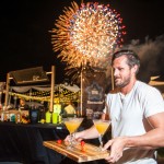 Plenty to savor at Taste of Cayman Dan Hollis, of Margaritaville, delivers some of his award-winning drinks to judges in the mixology competition as fireworks fill the air at the annual Taste of Cayman at Festival Green at Camana Bay. Mr. Hollis won the competition. - PHOTO: TANEOS RAMSAY