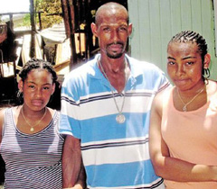 Johnny Buttrum and his daughters Hanielle, 12, and Janielle, 14, survey the wreckage of their George Town home which was destroyed by a fire in July, leaving 17 family members homeless.