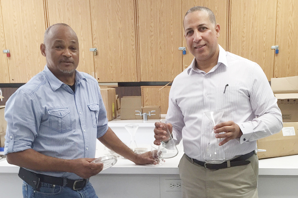 John Gray High School science teacher Godfrey Williams accepts the donation of science equipment from Health City's Richard Parchment.