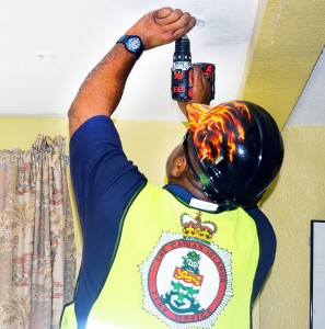 Acting senior divisional officer in the Fire Prevention Unit, Brevon Elliott, installs a free smoke detector in a home in Bodden Town.