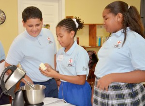 PIN students Justin Wright, Chaaya Ferguson and Jahsara Henry work as a team while making cupcakes.