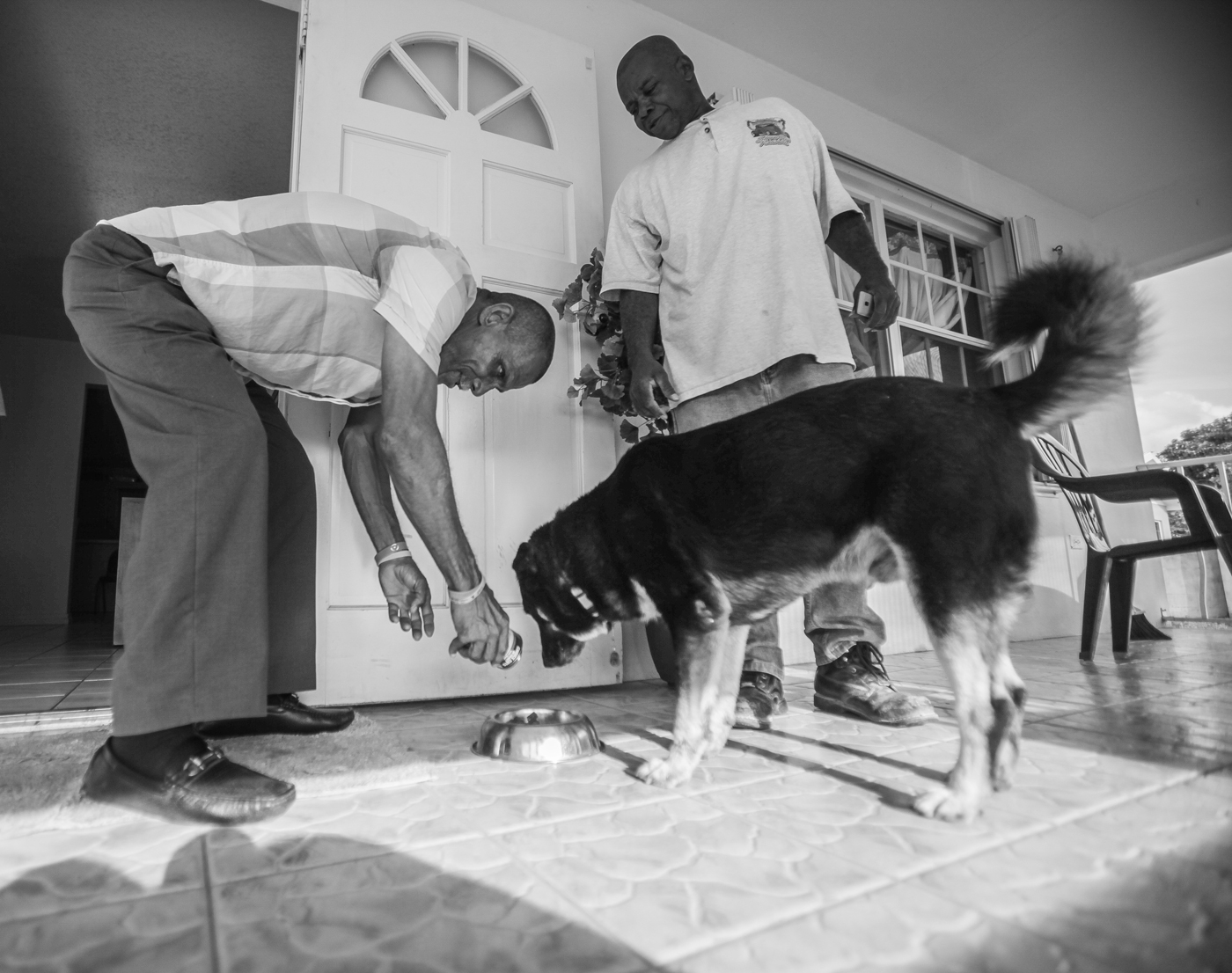 House manager Brent Hydes and Jason Dixon, a resident, feed one of the home's dogs. Around 25-30 people, many of them former inmates, all of them struggling with substance abuse, come through the home each year.