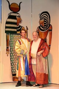 Joseph, played by Jared McIntosh, and his father, played by Richard De Lacey, stand before two of the impressively painted set pieces.