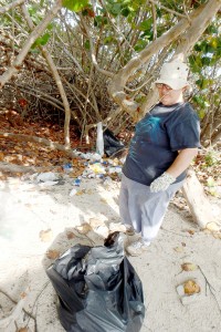 Paula Malone lends a helping hand to clear rubbish from the back of the restroom building at the Brac Public Beach. - Photos: Kathleen Bodden-Harris