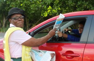Mae Thompson sells a Cayman Compass newpaper to an early morning commuter. Ms. Thompson was honored with Mother's Day gifts by Westin employees on Friday. - Photo: Jewel Levy
