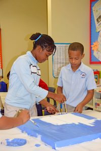 Young Heritage Arts program students Kelly Sauntie and Desmon Campbell prepare their artwork for the exhibition.