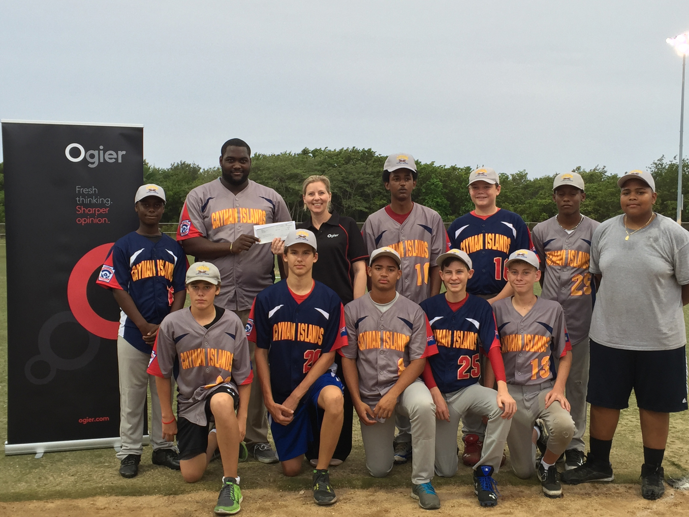 Ogier Partner Rachael Reynolds hands over a check to the Cayman Islands Little League team.