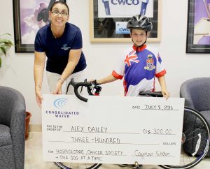 Alex Dailey accepts a $300 donation from Tracey Ebanks of Cayman Water.