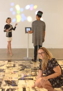National Gallery curator Emé Paschalides and assistant curator Kerri-Anne Chisholm, on the iPad, highlights an interactive digital art piece titled, 'Synesthesia (2016)' by artist William Verhoeven. Kaitlyn Elphinstone, on the floor, inspects the work of artist Aston Ebanks. - PHOTO: JEWEL LEVY