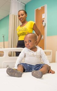 Mchaendel Gilot, 1, with his cousin Berline Valcin at the Health City Cayman Islands hospital in mid-August just before his procedure. – Photo: Taneos Ramsay