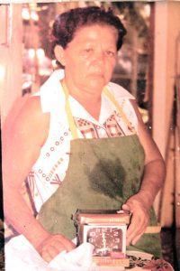 An earlier photo of Reina Watler, in her apron and holding a new clock, which she used to time cakes in the oven.
