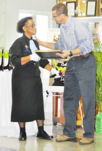 Director of the Lightbearers Club Chamayrane Williams presents an award to Woody Foster.