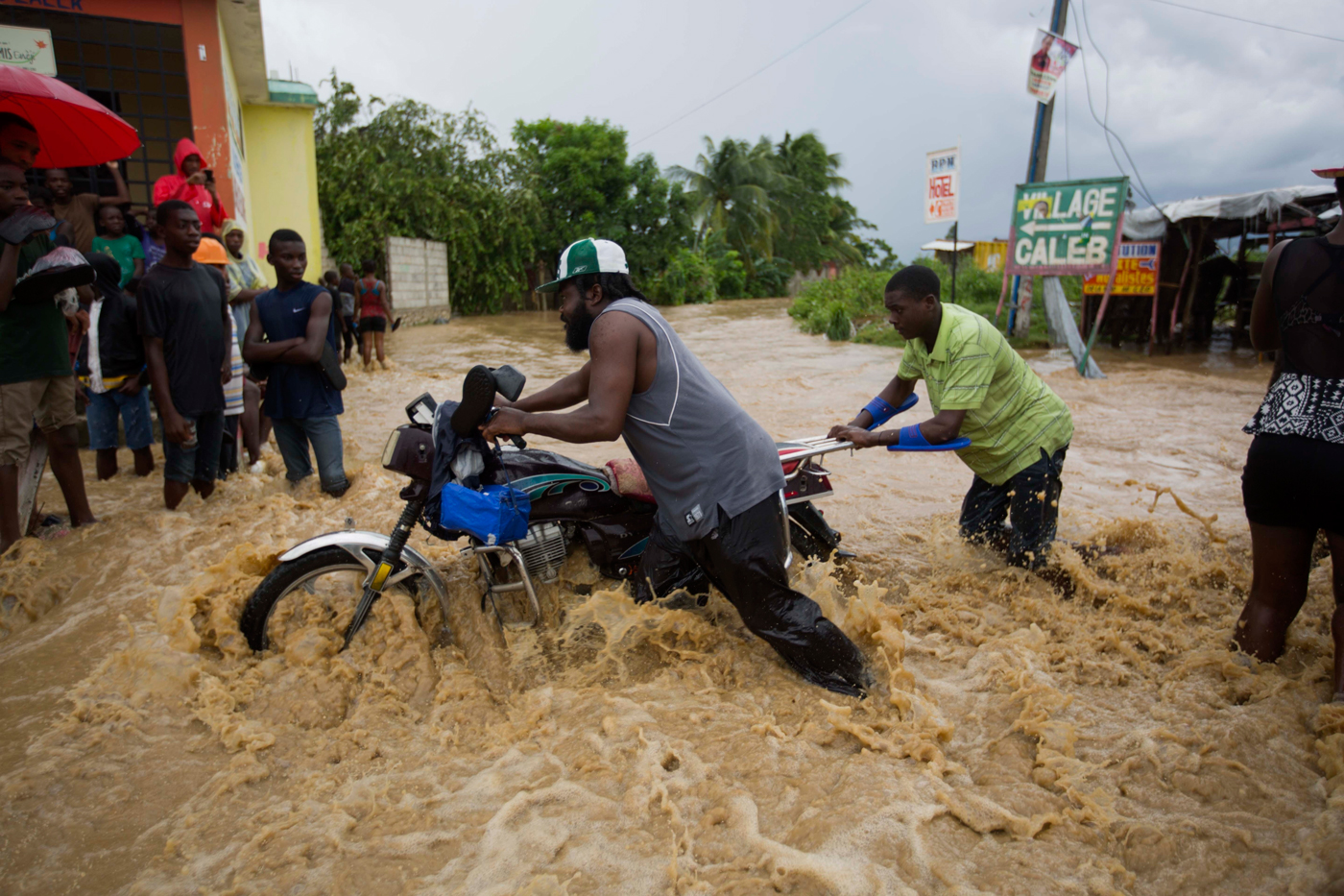 Men push a motorbike through a street flooded by a river that overflowed from heavy rains caused by Hurricane Matthew in Leogane, Haiti, Wednesday, Oct. 5. - Photo: AP