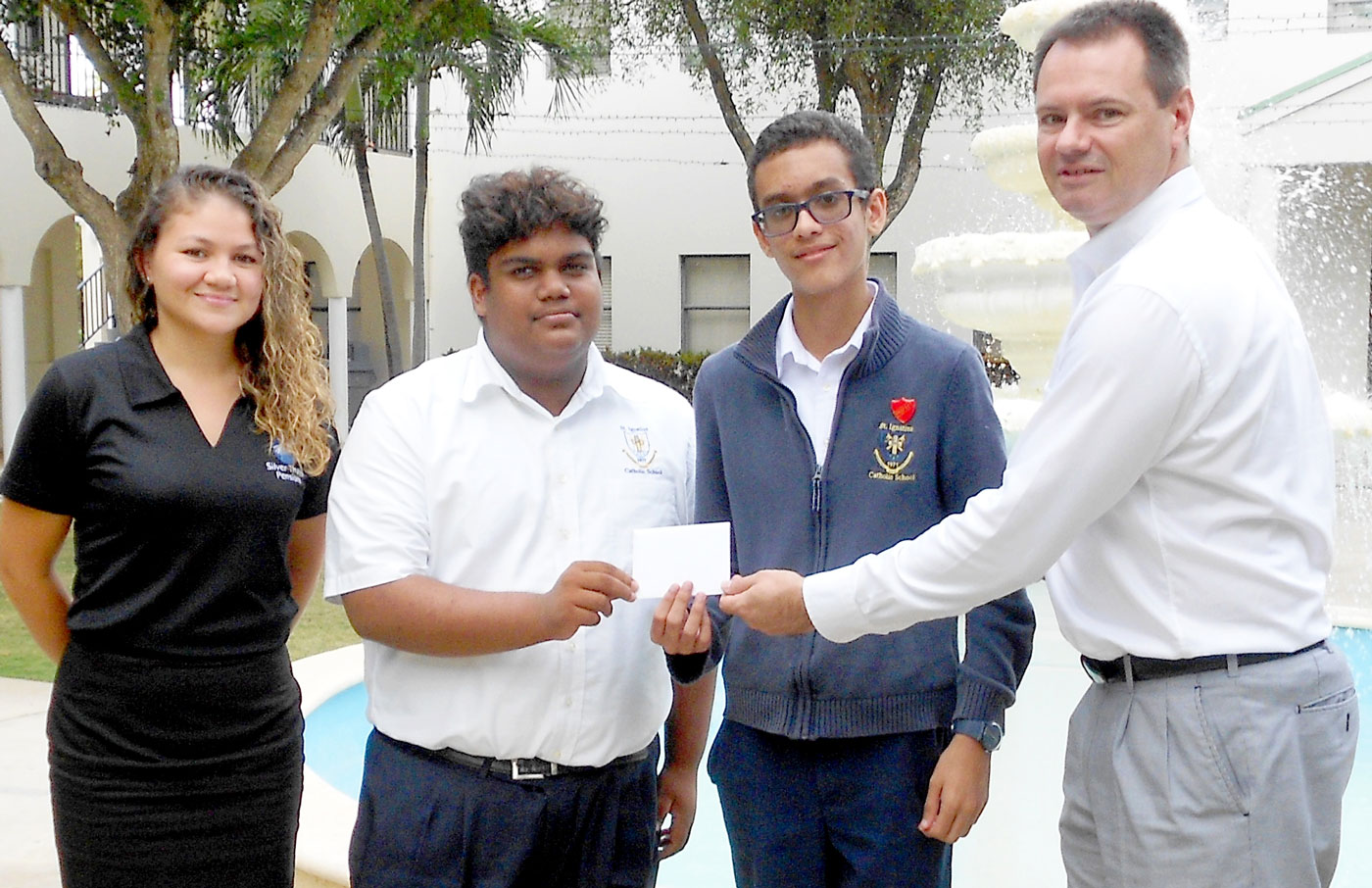 Alice Ramos of Silver Thatch Pensions with St. Ignatius students Aaron Fernandes and Enrique McCoy, who receive a gift certificate from Richard Ellison, director of business development at OneTRADEx.