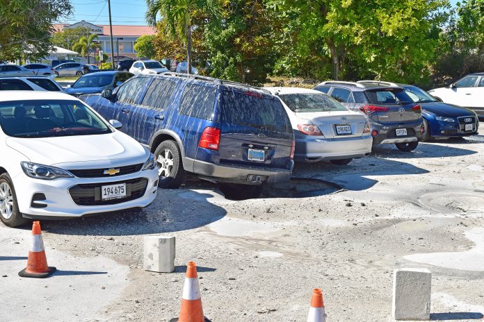 A vehicle hangs precariously over a sinkhole that appeared under