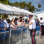 Split shopping shifts announced as 4 new coronavirus cases confirmed Police ensure customers adhere to social distancing rules as a large line builds up outside Foster's in West Bay