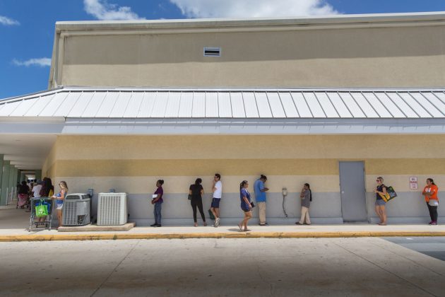 Shoppers wait for access to Kirk Market amid new social distancing rules Tuesday.