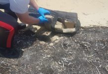 Cocaine tides: Millions of dollars worth of drugs wash up in Cayman Police collect cocaine packages from a beach in East End in April 2020 while Cayman was under lockdown restrictions. Throughout 2020, police recovered 137 pounds of cocaine that washed up on local beaches. - Photo: RCIPS