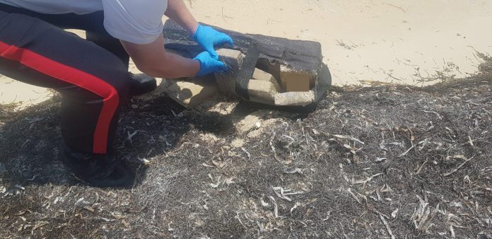 Police collect cocaine packages from a beach in East End in April 2020 while Cayman was under lockdown restrictions. Throughout 2020, police recovered 137 pounds of cocaine that washed up on local beaches. - Photo: RCIPS